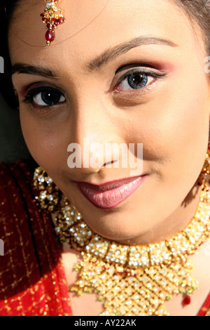 A young woman smiles while wearing the kind of jewellry that can typically be seen at Indian weddings. Stock Photo