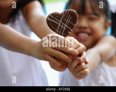 Close-up of two girls holding a heart shaped lollipop Stock Photo