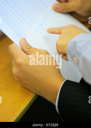 Close-up of a man's hands holding documents with a woman's hand pointing on it Stock Photo