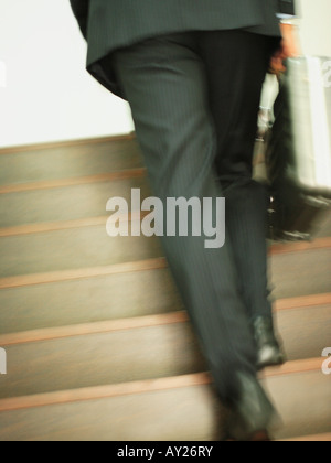 Low section view of a businessman moving up on steps and carrying a briefcase Stock Photo