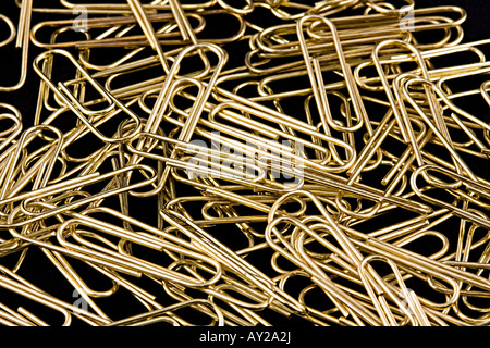 A pile of gold paperclips lay on a black background. Stock Photo