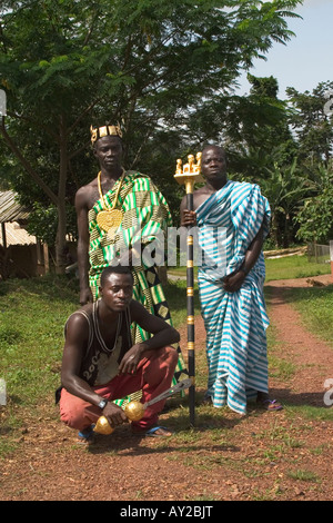 African chief in Kente cloth in his village with his linguist holding golden staff of office and his sword bearer, Ghana Stock Photo