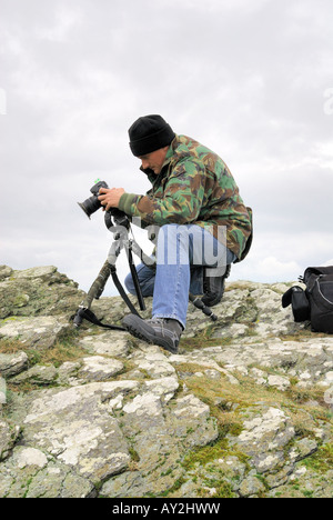 A photographer at work on an overcast day using a tripod and checking his images on the digital cameras LCD screen Stock Photo
