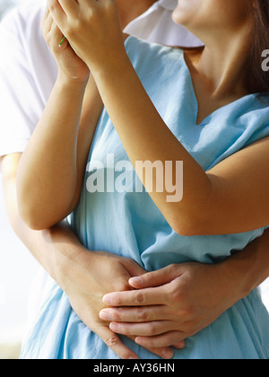 Mid section view of a mid adult man embracing a mid adult woman Stock Photo