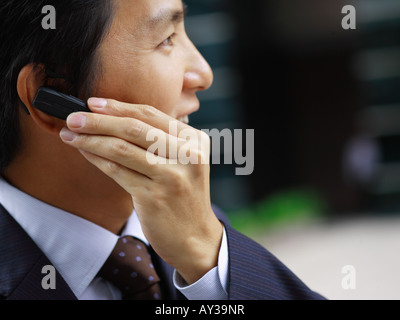 Side profile of a businessman using a bluetooth device and smiling Stock Photo