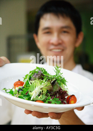 Portrait of a chef holding a plate of salad and smiling Stock Photo