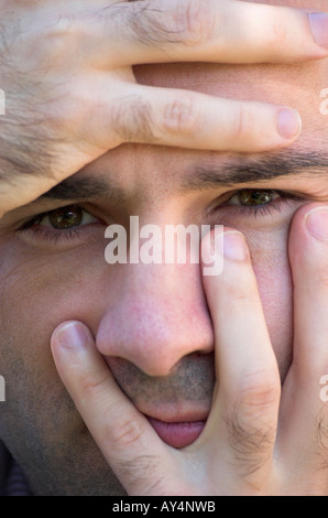 Man spreading fingers across face close up Stock Photo