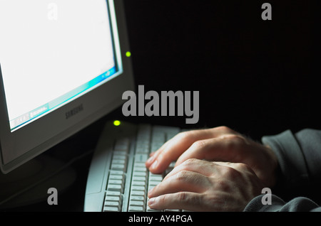 Man using computer hands illuminated by computer monitor Stock Photo