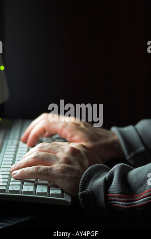 Man using computer hands illuminated by computer monitor Stock Photo