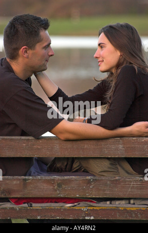 Young couple sitting on bench embracing face to face side view Stock Photo