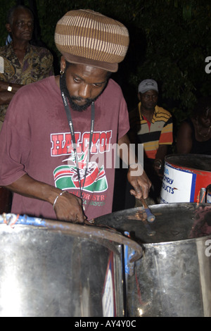 Drummer wearing rasta hat part of Steel band playing at Shirley Heights Antigua Caribbean Stock Photo