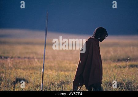 A Maasai tribesman is a solitary figure on a Tanzania plain as the sun sets Stock Photo