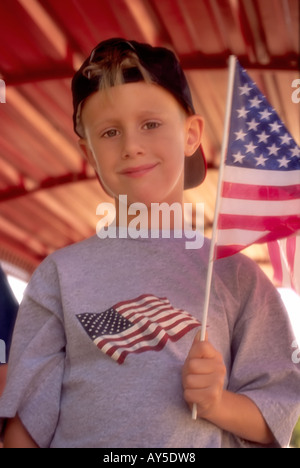 A patriotic young boy waves the American flag, at the 4th of July parade in Capitan, New Mexico. Stock Photo