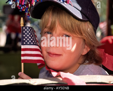 A young patriotic boy waves the American flag, at the 4th of July parade in Capitan, New Mexico. Stock Photo