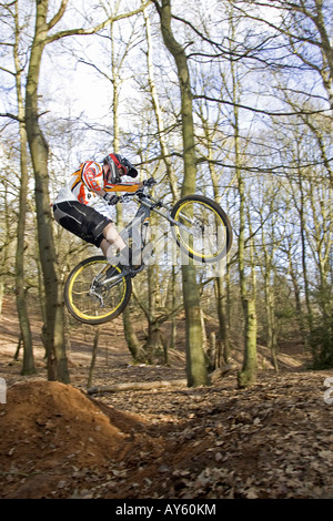 A mountain biker jumps his mountain bike over a dirt jump Stock Photo