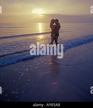 couple embrace on beach at sunset Stock Photo