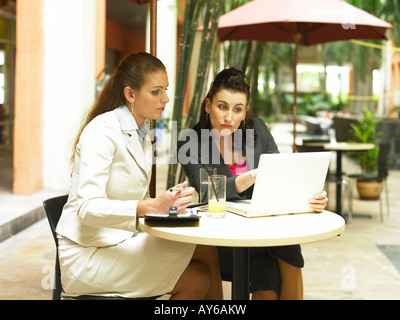 A lady is pointing something on the screen, while the other lady writing it Stock Photo