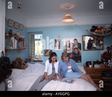 Teenage girls in bedroom,reading magazines and chatting, Ascot, Berkshire, England, United Kingdom Stock Photo