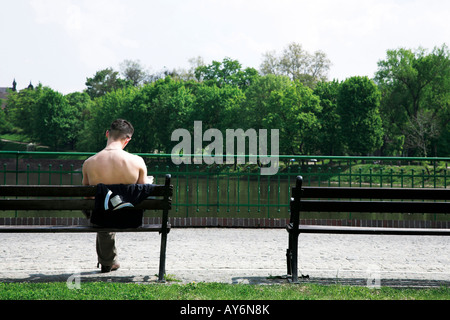 Young man sitting on a bench near river Stock Photo