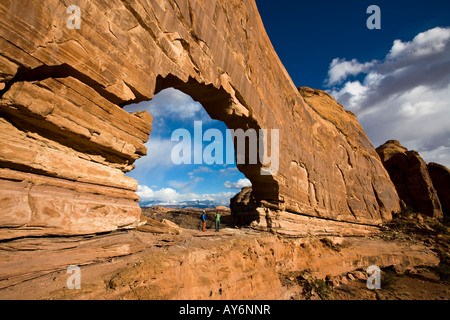 two hikers stand under Jeep Arch near Moab Utah Stock Photo