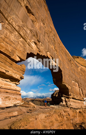 two hikers stand under Jeep Arch near Moab Utah Stock Photo