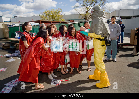 Multiethnic volunteer victims in disposable clothing ask a fellow volunteer in protective clothing when they can get dressed Stock Photo