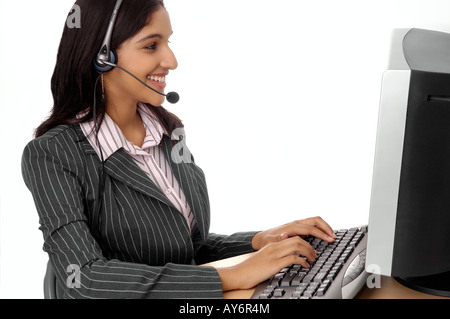 Attractive woman at computer with headset; customer service or telemarketer. Stock Photo
