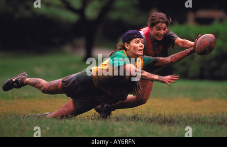 Two young women fight for the football in a game of touch football on a muddy field Stock Photo