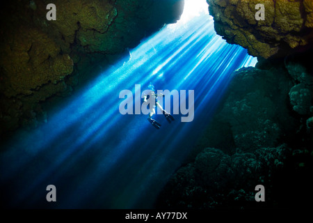 A scuba diver ascends a ladder of sunbeams through Custom Cave in the Russell Islands, part of the Solomon Islands. Stock Photo