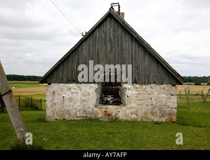 Small barn in pasture. stone walls and wood roof. Cloudy sky. Stock Photo