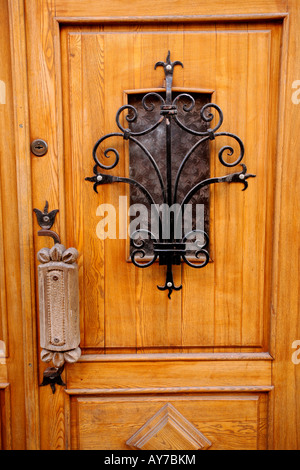 Wood door with ornate wrought iron lattice work over small window. Large metal handle Stock Photo