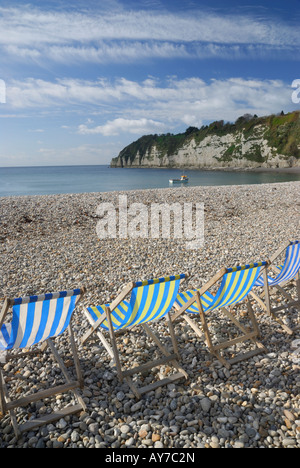 View of Beer beach in Devon, UK, with blue deckchairs in the foreground and a small boat in the sea Stock Photo