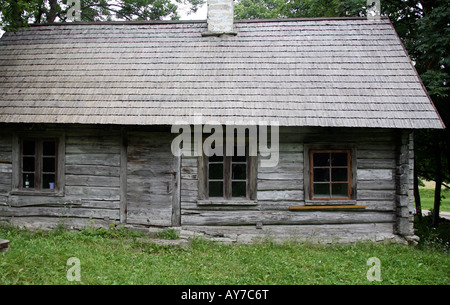 Rustic old wood house or cottage, unpainted, grey walls and roof. Grass in foreground Stock Photo