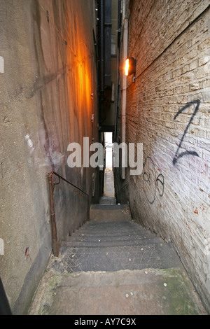 Wide angle shot of narrow alley with steps leading down onto road. Stock Photo