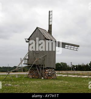 Windmill with rock filled base in a grass pasture cloudy day Stock Photo
