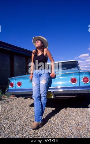 Young woman in torn blue jeans resting on a Chevrolet Belair car Cerillos New Mexico USA MR Stock Photo