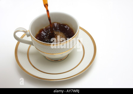 A sideview shot of a cup of coffee isolated on white coffe being poured into it Stock Photo