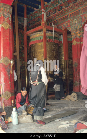 woman pilgrim prostrating outside the Jokhang Temple in Lhasa ,Tibet ,Huge golden prayerwheel Stock Photo