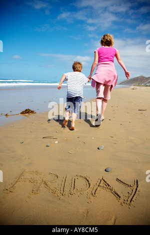 the word friday drawn in the sand with people running away ready for the weekend Stock Photo