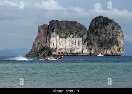 Longtail boat at speed drives past rocky limestone islet off Ko Ngai island Thailand Stock Photo