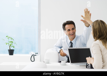 Business associates giving each other high-five in office Stock Photo