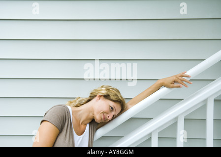 Woman leaning head against railing, smiling, looking away Stock Photo