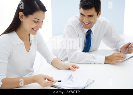 Two business associates studying graph together, smiling Stock Photo