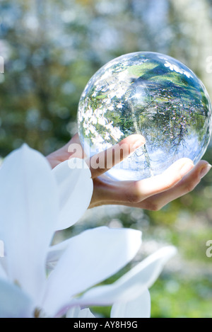 Woman holding glass sphere in hand, cropped view Stock Photo