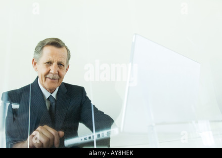 Businessman using laptop computer, smiling at camera, low angle view Stock Photo