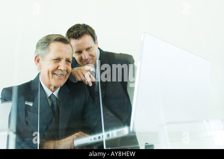 Two businessmen looking at laptop computer together, both smiling, low angle view Stock Photo