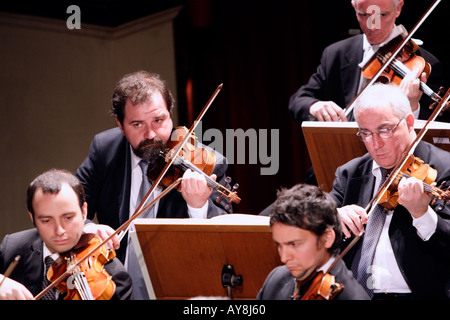 five male violinists performing with a symphony orchestra in formal dress Stock Photo