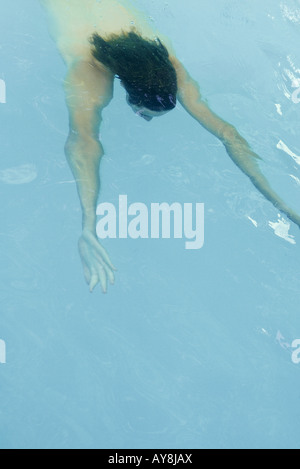 Man swimming underwater in pool, arms stretched in front of him Stock Photo