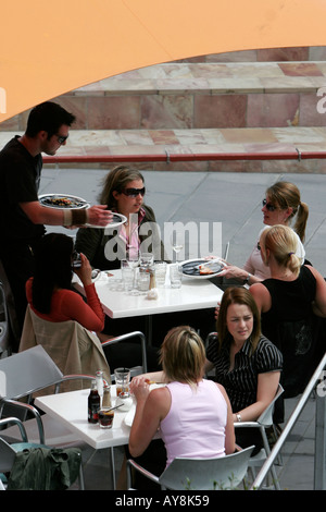 Waiter attends young women having lunch outside Melbourne Victoria Australia Stock Photo