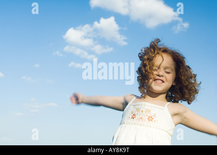 Young girl jumping in the air, arms outstretched, eyes closed, waist up Stock Photo